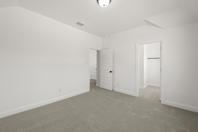 unfurnished bedroom with lofted ceiling, a spacious closet, and light carpet