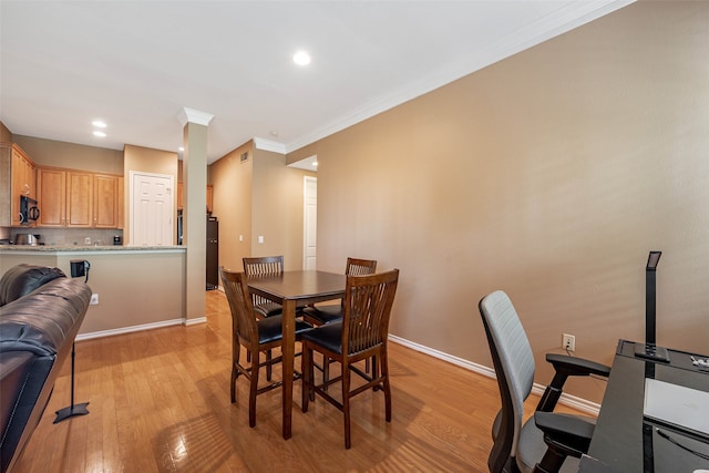 dining space featuring ornamental molding and light wood-type flooring