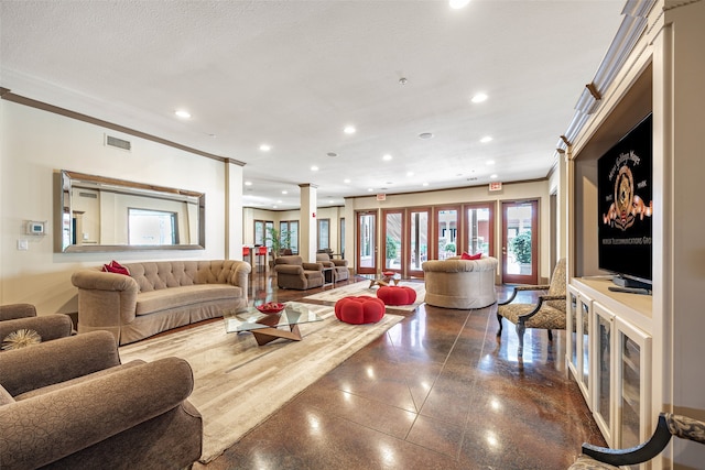 living room with crown molding, a textured ceiling, and decorative columns