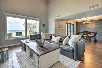 living room featuring a towering ceiling, a notable chandelier, hardwood / wood-style flooring, and brick wall