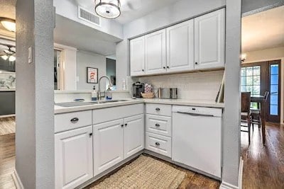 kitchen featuring white cabinetry, light hardwood / wood-style flooring, tasteful backsplash, and dishwasher