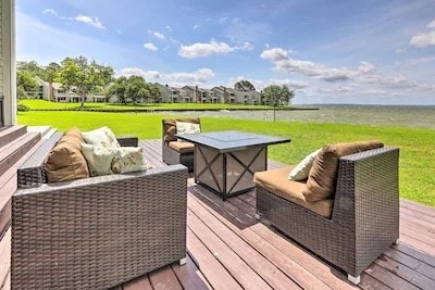 wooden terrace with a water view and a lawn