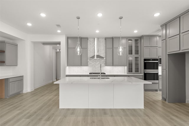 22067 Breakwater Ln, Porter, TX 77365 - kitchen featuring wall chimney exhaust hood, gray cabinetry, double oven, recessed lighting, and a kitchen island with sink