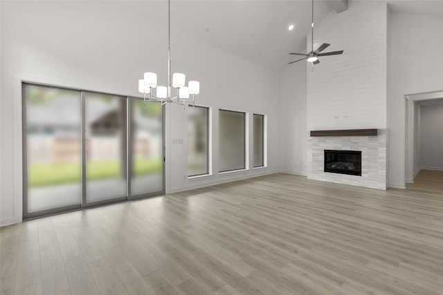 22067 Breakwater Ln, Porter, TX 77365 - unfurnished living room with high vaulted ceiling, a chandelier, light wood finished floors, a ceiling fan, and a tiled fireplace