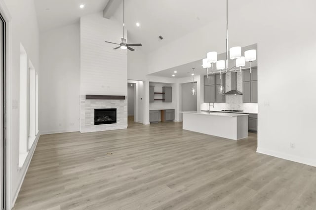22067 Breakwater Ln, Porter, TX 77365 - unfurnished living room featuring high vaulted ceiling, a sink, light wood-style floors, baseboards, and beam ceiling