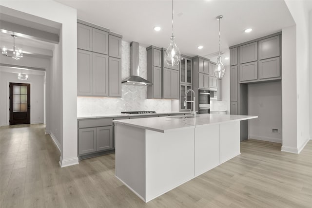 22067 Breakwater Ln, Porter, TX 77365 - kitchen with gray cabinets, wall chimney range hood, a sink, tasteful backsplash, and light wood-type flooring