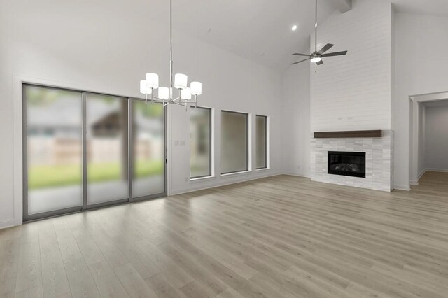 22067 Breakwater Ln, Porter, TX 77365 - unfurnished living room featuring high vaulted ceiling, a chandelier, light wood finished floors, ceiling fan, and a tiled fireplace