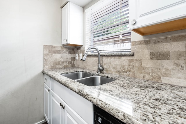 kitchen featuring white cabinetry, tasteful backsplash, light stone countertops, and sink