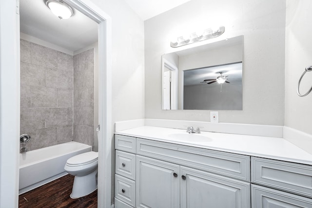 full bathroom with tiled shower / bath, ceiling fan, wood-type flooring, toilet, and vanity