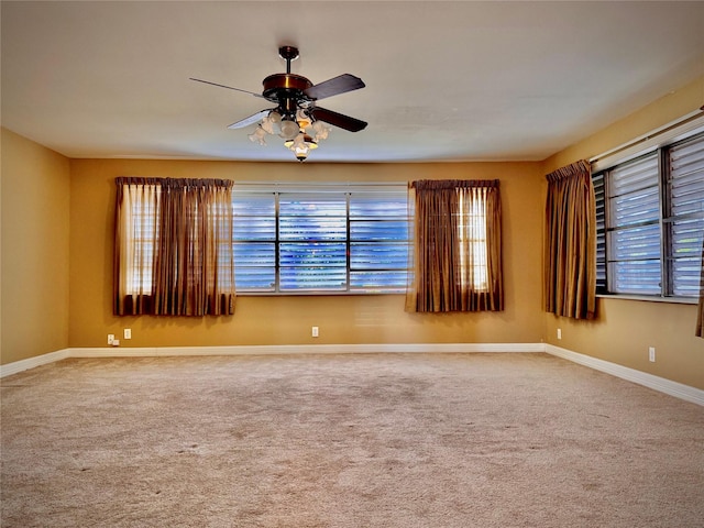 spare room with baseboards, ceiling fan, and carpet