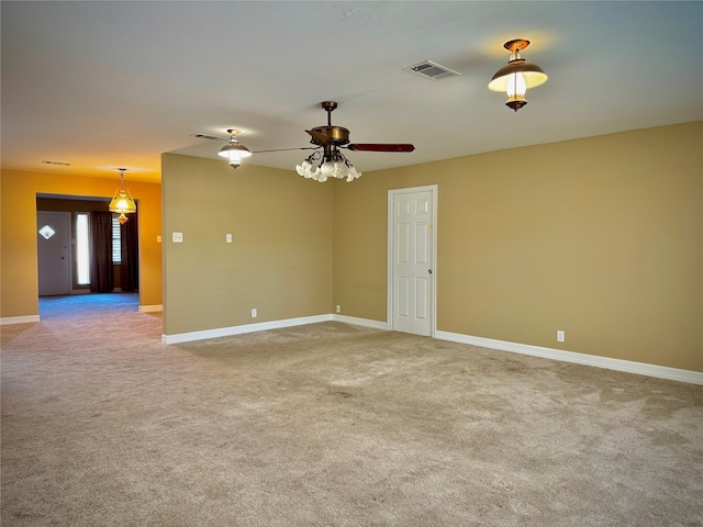 carpeted empty room with baseboards, visible vents, and ceiling fan