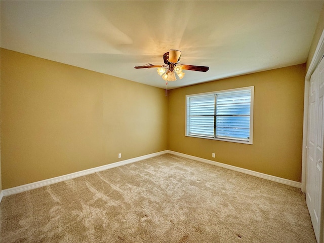 spare room featuring carpet flooring, a ceiling fan, and baseboards