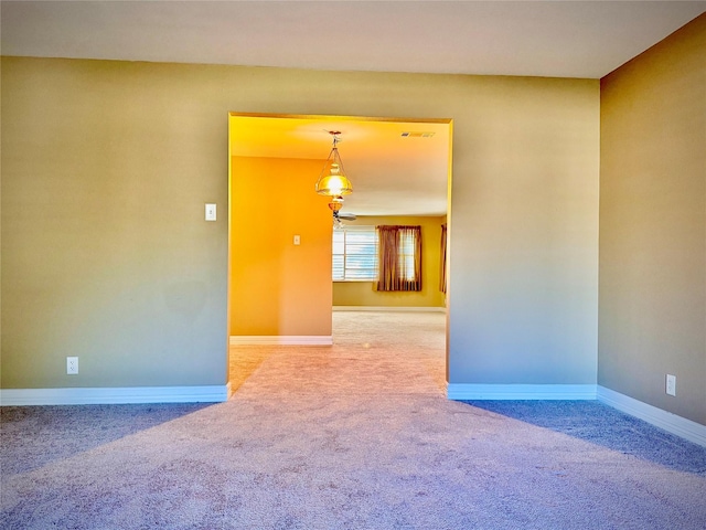 spare room with carpet flooring, baseboards, and visible vents
