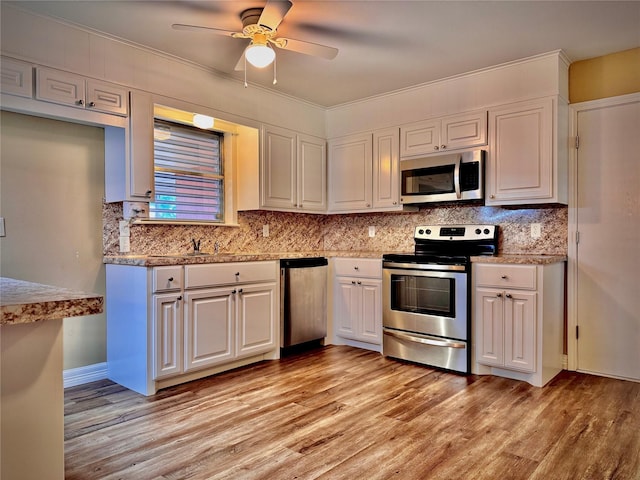 kitchen with a ceiling fan, light wood finished floors, appliances with stainless steel finishes, and decorative backsplash