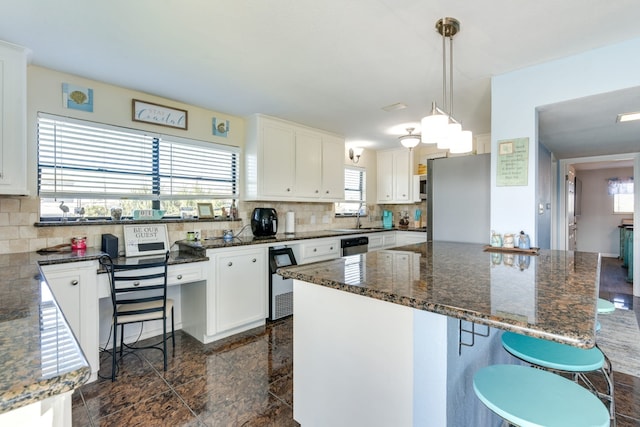 kitchen featuring tasteful backsplash, sink, white cabinetry, decorative light fixtures, and stainless steel refrigerator