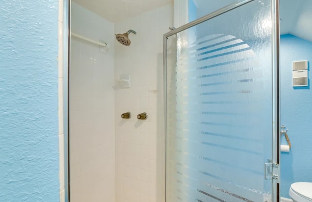 bathroom with toilet, a shower with shower door, and vaulted ceiling