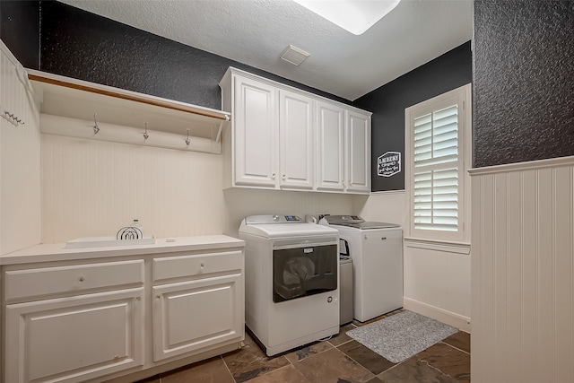 clothes washing area with washer and dryer and cabinets