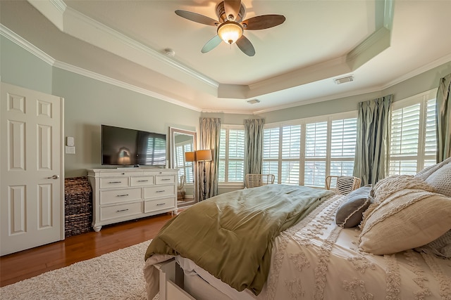 bedroom with ceiling fan, wood-type flooring, a tray ceiling, and multiple windows