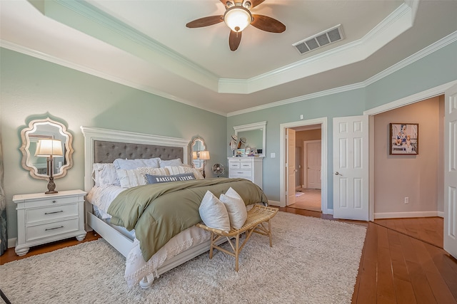 bedroom featuring a raised ceiling, ceiling fan, crown molding, and light wood-type flooring