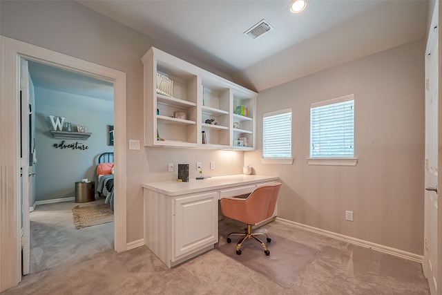 office area with built in desk, light carpet, and vaulted ceiling