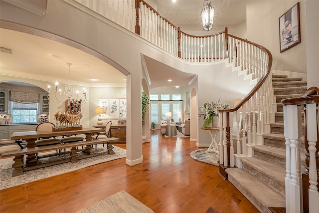 foyer entrance featuring wood-type flooring, a wealth of natural light, crown molding, and a high ceiling