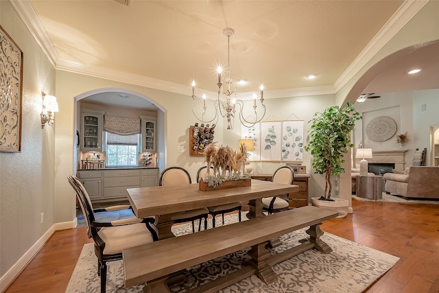 dining area with ceiling fan with notable chandelier, hardwood / wood-style flooring, and ornamental molding