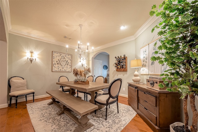 dining room with an inviting chandelier, light hardwood / wood-style flooring, and crown molding