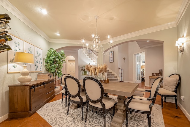 dining area with hardwood / wood-style floors, crown molding, and a chandelier