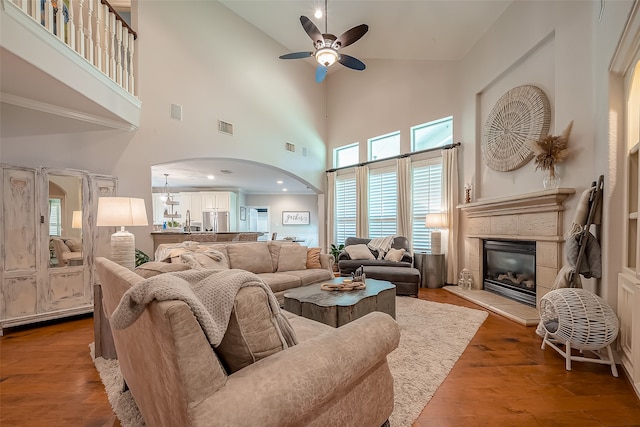 living room with ceiling fan, a towering ceiling, and light hardwood / wood-style flooring