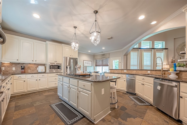 kitchen with appliances with stainless steel finishes, a breakfast bar, pendant lighting, white cabinets, and a kitchen island