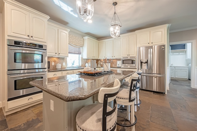 kitchen featuring appliances with stainless steel finishes, tasteful backsplash, dark stone counters, decorative light fixtures, and a center island