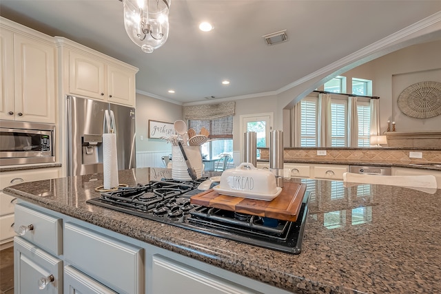 kitchen featuring white cabinets, crown molding, dark stone countertops, appliances with stainless steel finishes, and tasteful backsplash