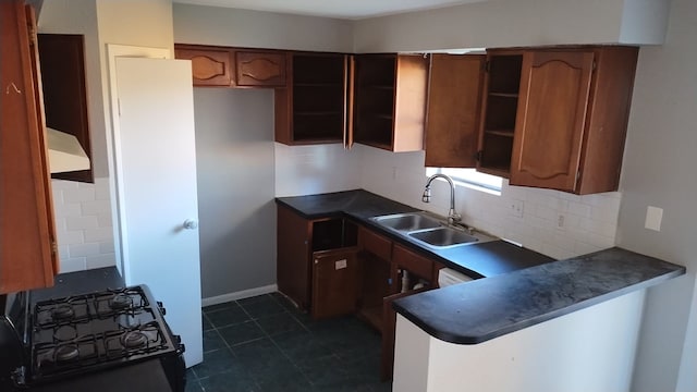 kitchen with custom exhaust hood, decorative backsplash, dark tile patterned floors, black range with gas stovetop, and sink