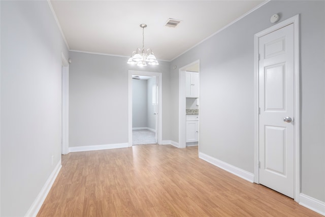 empty room featuring light hardwood / wood-style floors, a notable chandelier, and ornamental molding