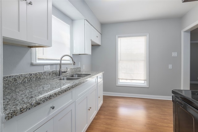 kitchen featuring light stone countertops, sink, light wood-type flooring, white cabinets, and black / electric stove