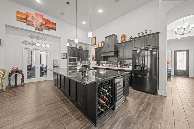 kitchen with appliances with stainless steel finishes, french doors, a large island, custom exhaust hood, and dark hardwood / wood-style floors