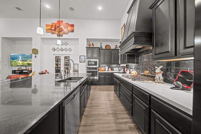 kitchen featuring appliances with stainless steel finishes, sink, backsplash, pendant lighting, and custom range hood