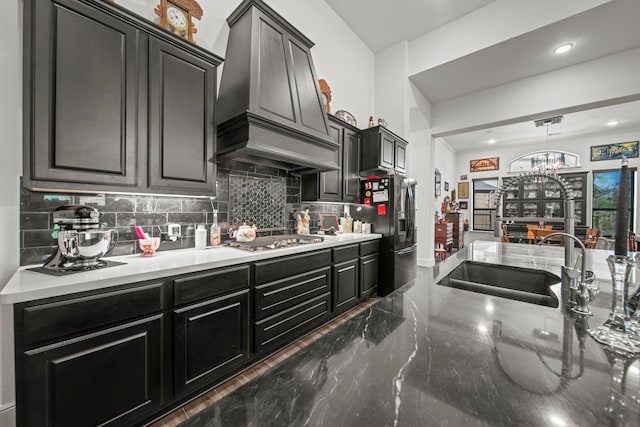 kitchen with sink, hanging light fixtures, stainless steel appliances, decorative backsplash, and premium range hood