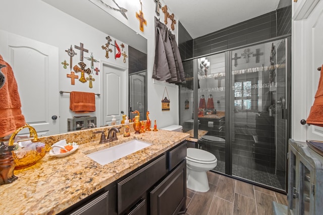 bathroom featuring toilet, vanity, and a shower with door