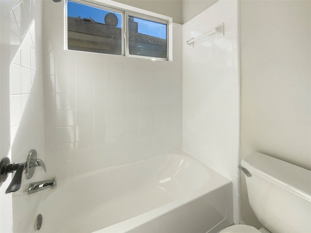 bathroom with toilet and tiled shower / bath combo