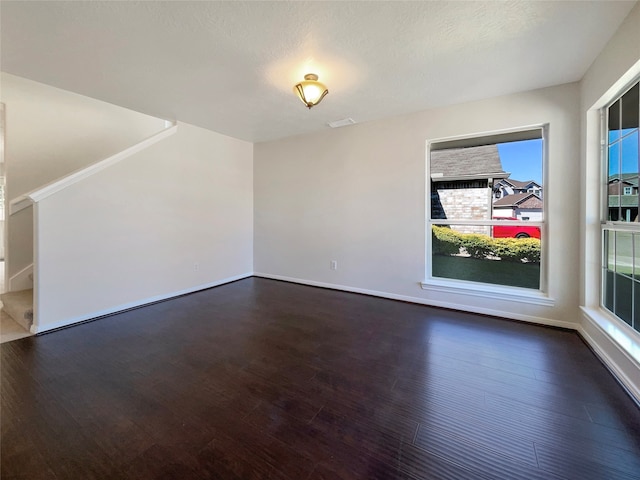 unfurnished room with a textured ceiling and dark hardwood / wood-style floors