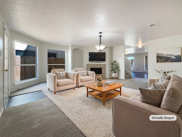 living room with a textured ceiling, light colored carpet, and a tile fireplace