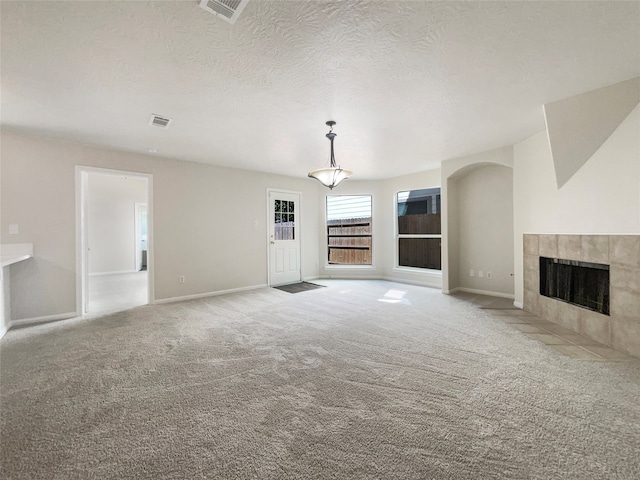 unfurnished living room with light carpet, a textured ceiling, and a fireplace