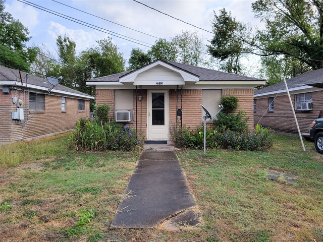 bungalow with a front yard and cooling unit