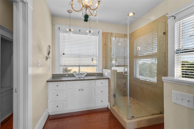 bathroom with vanity, a notable chandelier, walk in shower, and hardwood / wood-style floors