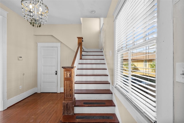 stairway with a notable chandelier and hardwood / wood-style floors