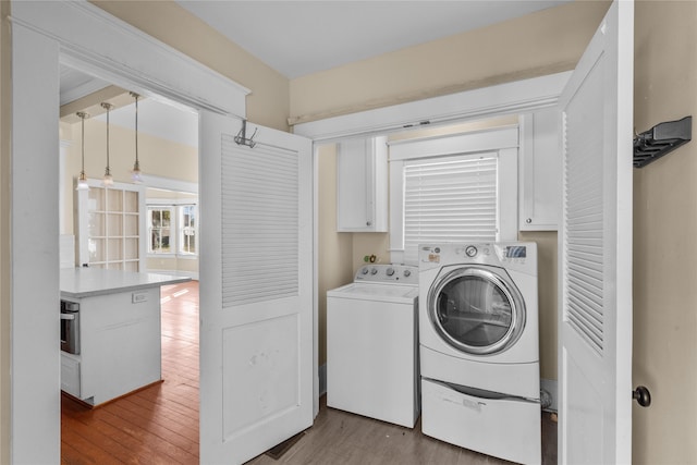 laundry room featuring cabinets, independent washer and dryer, and light wood-type flooring