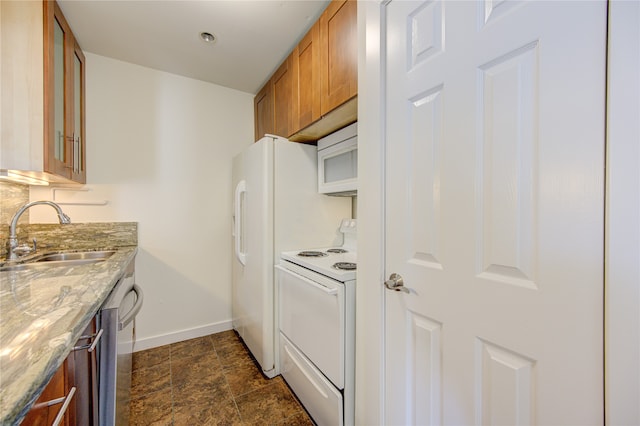 kitchen with sink, light stone countertops, and white appliances