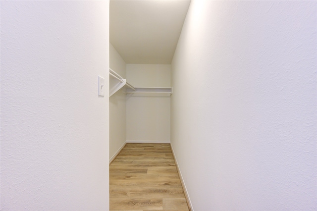 walk in closet with light hardwood / wood-style flooring