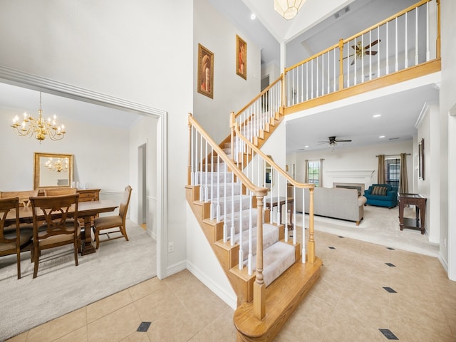 stairs featuring a towering ceiling, ornamental molding, a chandelier, and carpet flooring